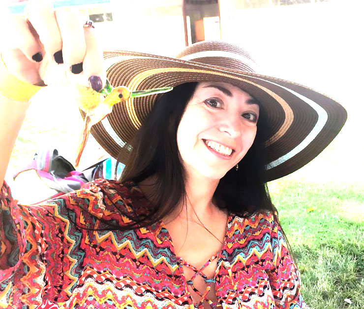 Stephanie Morgan smiling in a sun hat with a hummingbird
